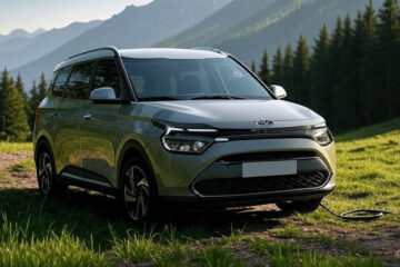 Kia Carens Clavis EV in a scenic mountain backdrop with charging cable plugged in – front three-quarter angle view